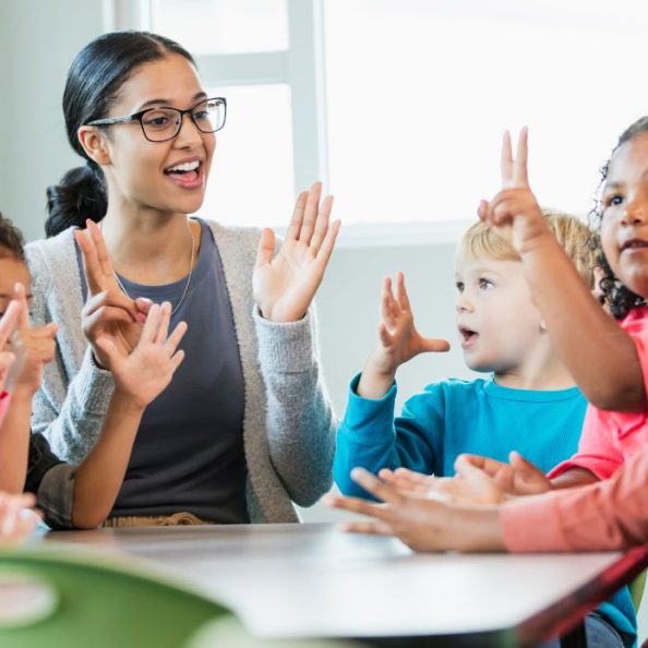 Première rentrée d'une jeune enseignante assise à une table entourée de jeune enfants