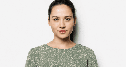 Portrait de la jeune enseignante interviewée, jeune femme brune de 25 ans. elle porte une blouse fleurie et regarde la caméra.