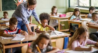 Salle de classe élémentaire, une jeune enseignante parle à un élève
