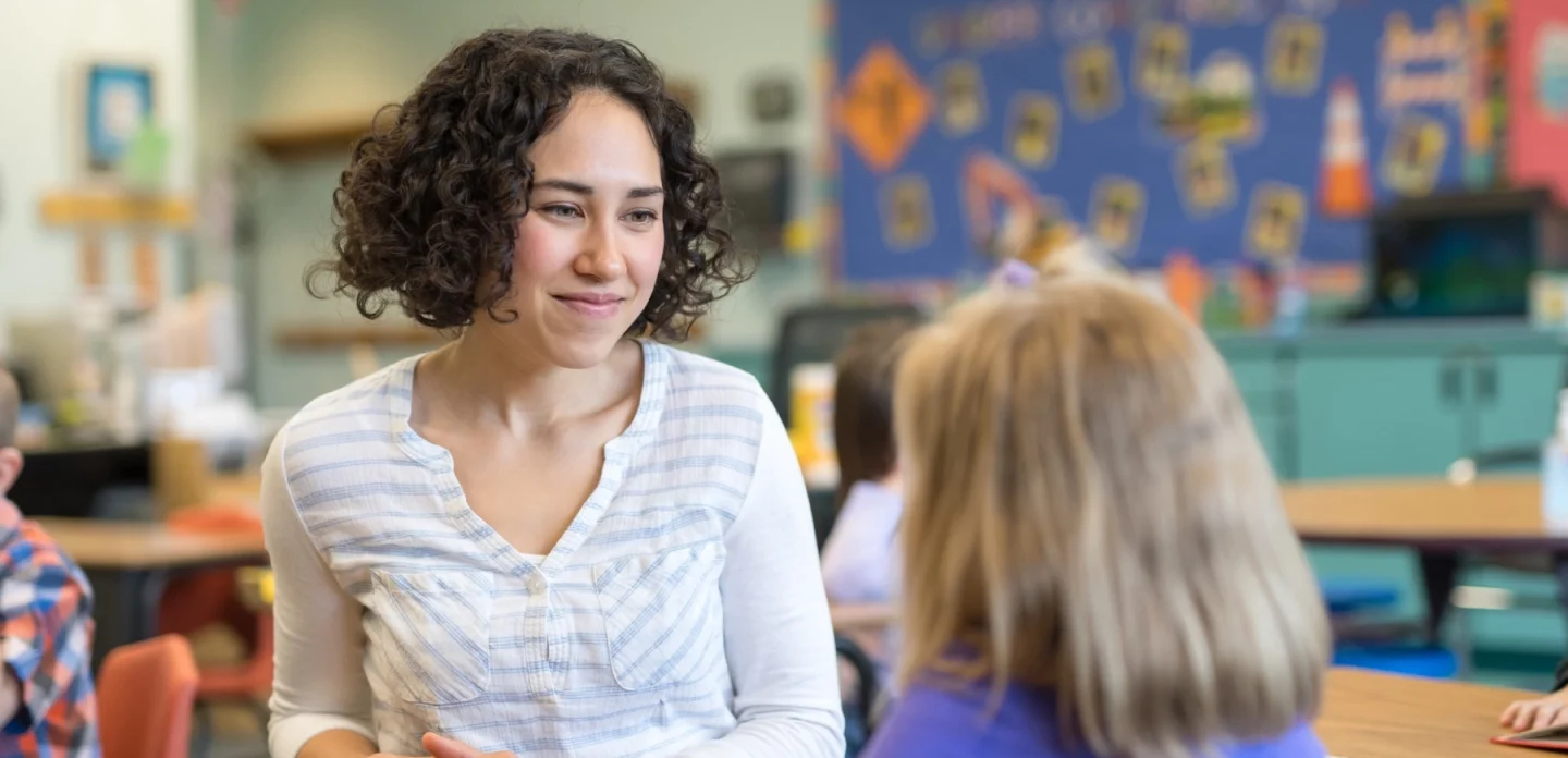 Salle de classe de primaire, une enseignante face à une élève vue de dos